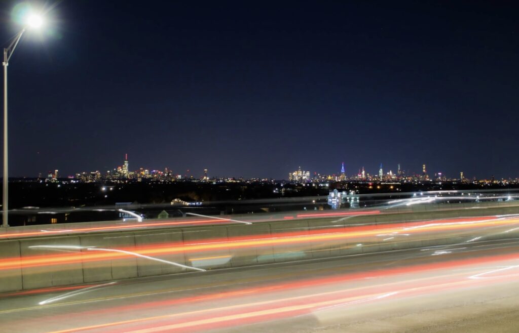 Nighttime view of New York City skyline seen from Belt Parkway near Flor de Fred