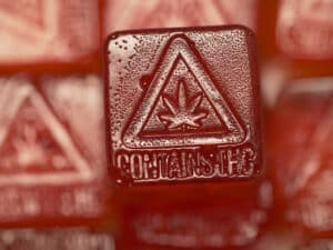 A close-up of a red cannabis gummy with a THC warning.